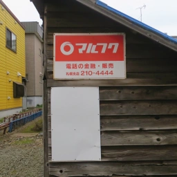 マルフク看板「電話の金融・販売 札幌支店」。下に色あせた縦型のマルフク看板もある