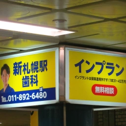 柱の4面に設置されているうちの2面。「新札幌駅歯科」「インプラント無料相談」