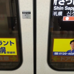 ドアステッカー。「インプラント新札幌駅」と、顔写真・電話番号が書かれたものの2枚